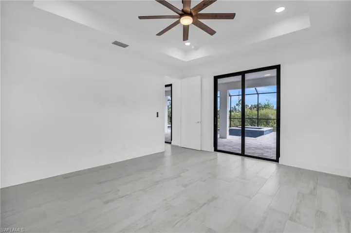 Spare room featuring a tray ceiling, recessed lighting, light wood-style floors, and ceiling fan