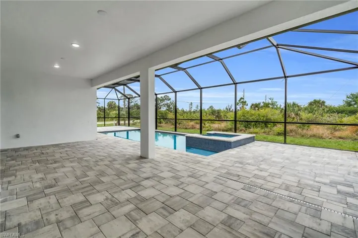 View of pool with glass enclosure, a patio area, and a pool with connected hot tub