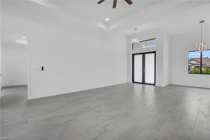 Unfurnished living room with wood finished floors, ceiling fan, a chandelier, french doors, and recessed lighting