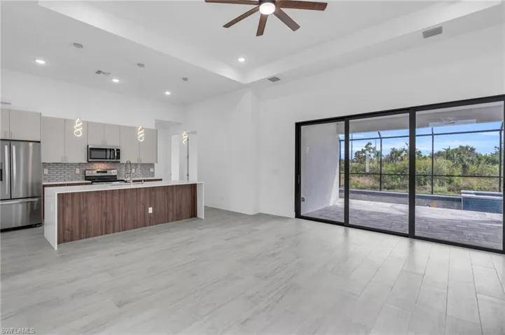 Kitchen featuring stainless steel appliances, modern cabinets, a raised ceiling, light countertops, and open floor plan