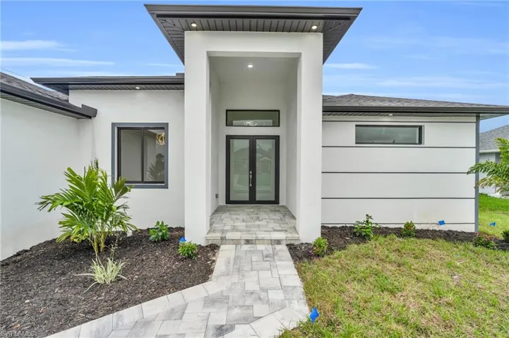 Doorway to property featuring stucco siding and a yard