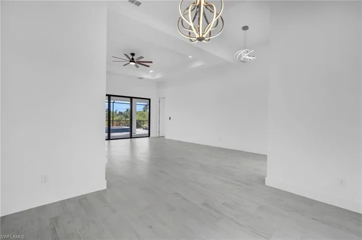 Unfurnished room with wood finished floors, a chandelier, a tray ceiling, and a ceiling fan