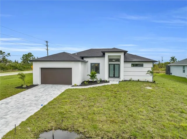Prairie-style home with a front yard, an attached garage, decorative driveway, roof with shingles, and stucco siding