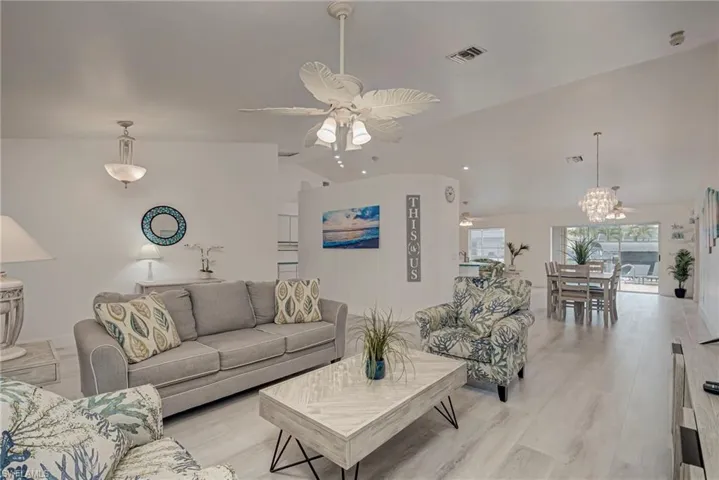 Living area with lofted ceiling, a ceiling fan, and light wood finished floors
