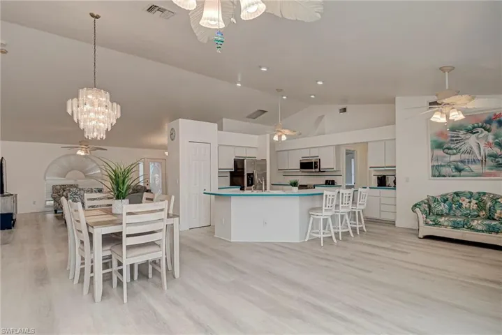 Kitchen with open floor plan, a ceiling fan, appliances with stainless steel finishes, light wood-style flooring, and a breakfast bar area