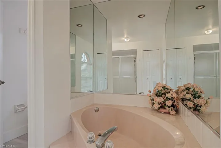 Bathroom with a closet, a stall shower, a garden tub, and recessed lighting
