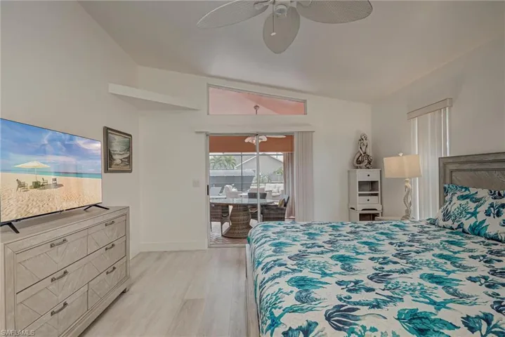 Bedroom with access to exterior, light wood-style floors, a ceiling fan, and vaulted ceiling