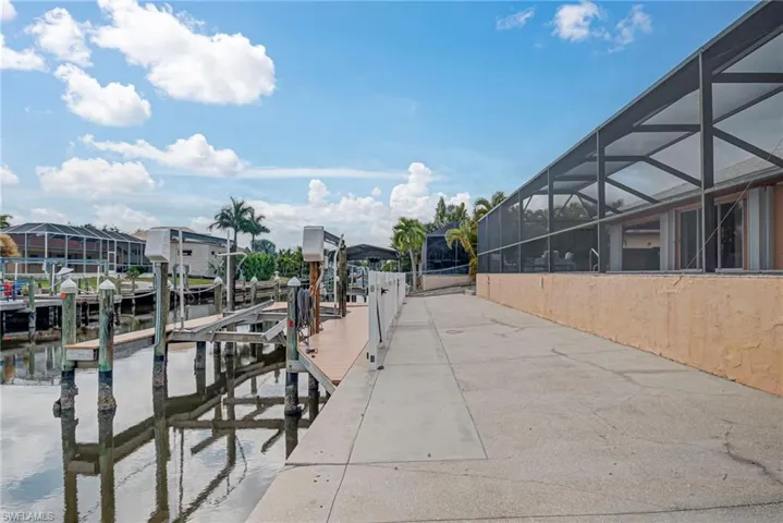 Dock area with boat lift, glass enclosure, and a sunroom