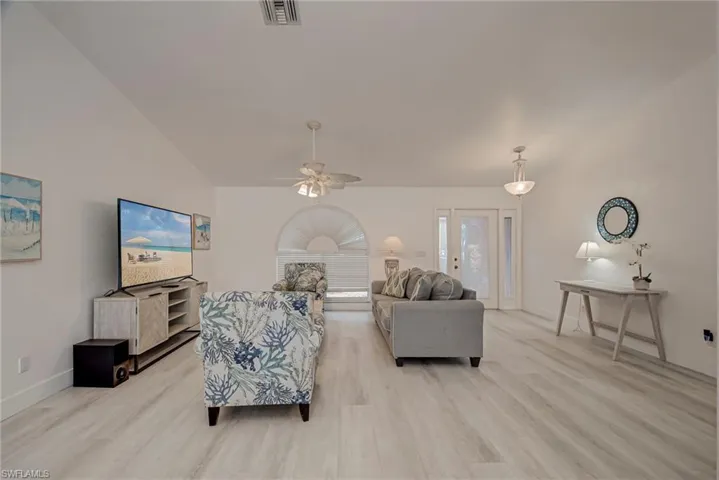 Living room featuring vaulted ceiling, ceiling fan, and light wood-style flooring