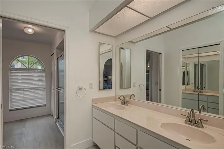 Full bathroom featuring double vanity, a shower stall, and light wood-style flooring