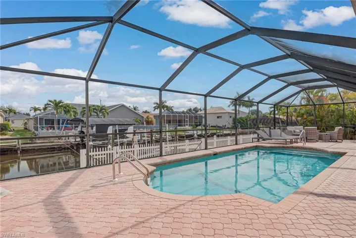Outdoor pool featuring a sunroom, a residential view, a patio, and glass enclosure