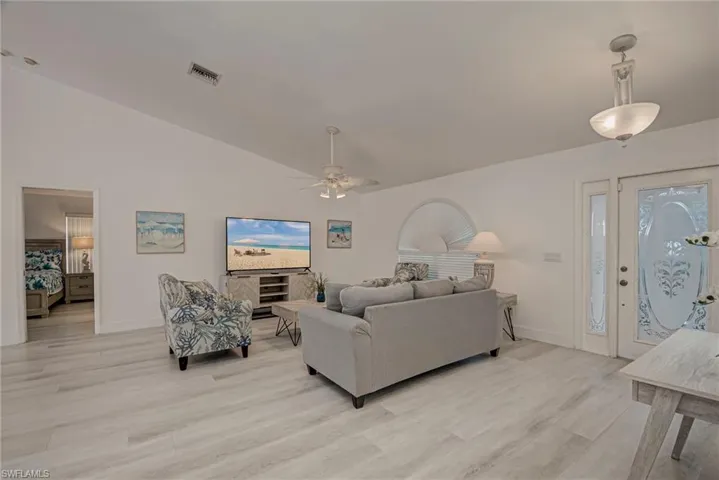 Living room with vaulted ceiling, light wood-type flooring, and ceiling fan