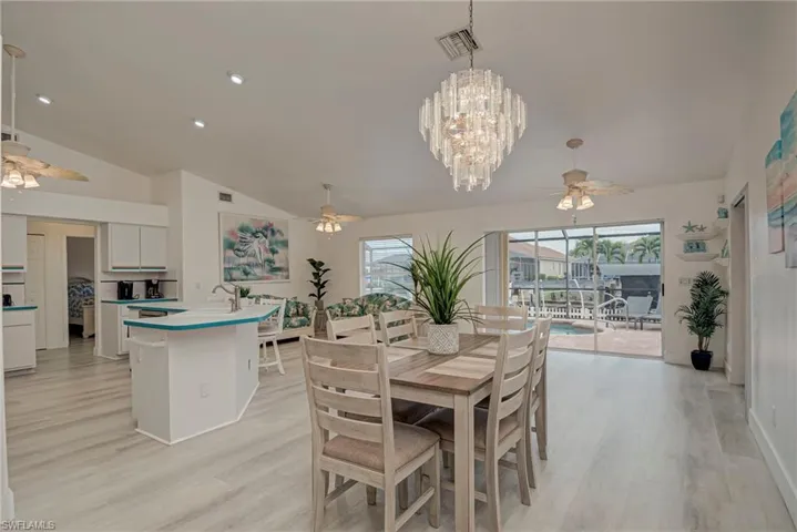 Dining space featuring ceiling fan, light wood finished floors, a chandelier, lofted ceiling, and recessed lighting