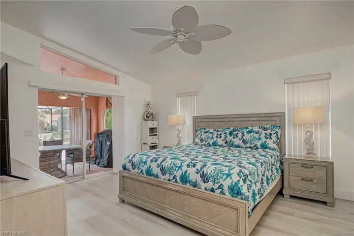 Bedroom with access to exterior, light wood-style floors, ceiling fan, and vaulted ceiling