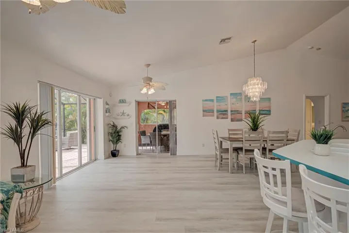 Dining room with lofted ceiling, light wood-style flooring, a chandelier, and ceiling fan