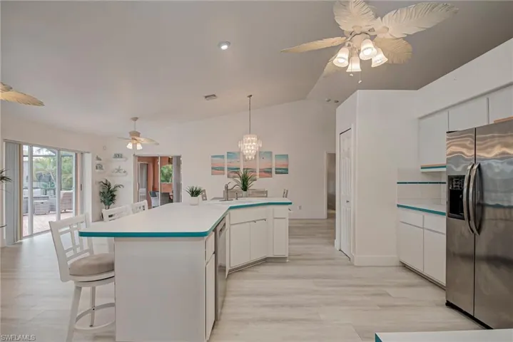 Kitchen featuring white cabinets, a ceiling fan, appliances with stainless steel finishes, a breakfast bar, and vaulted ceiling