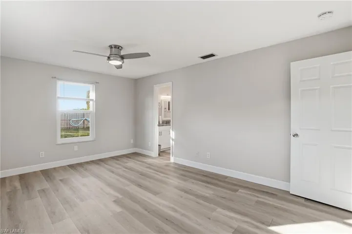 Unfurnished bedroom featuring a ceiling fan, light wood finished floors, and ensuite bathroom