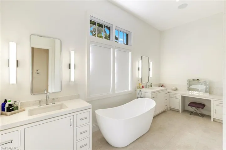 Bathroom featuring two vanities and a freestanding bath