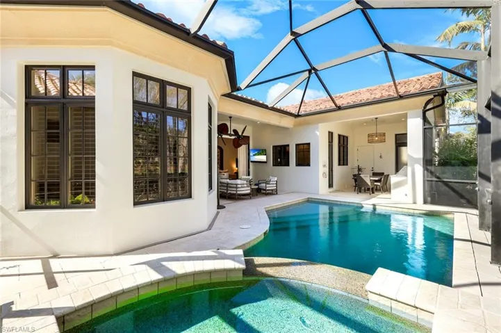 Combined pool / hot tub featuring a sunroom, a patio, an outdoor living / dining area, and a lanai