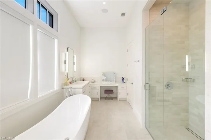 Bathroom with a shower stall, a soaking tub, vanity, and light tile patterned floors