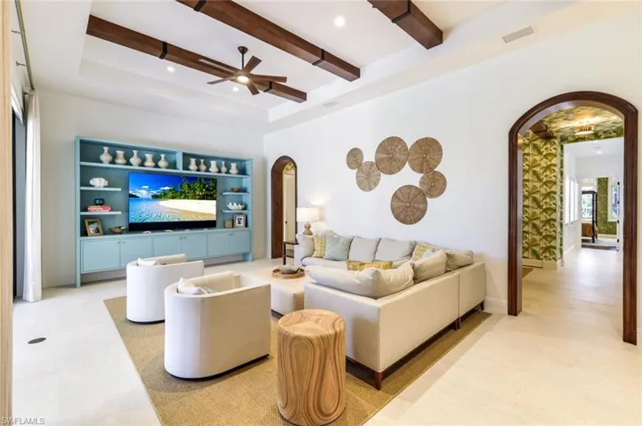 Living area featuring arched walkways, recessed lighting, beamed ceiling, ceiling fan, and built in shelves