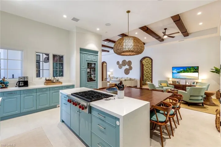 Kitchen with arched walkways, a kitchen island, beamed ceiling, stainless steel gas stovetop, and open floor plan