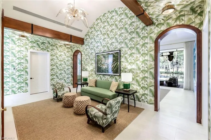 Living area with arched walkways, lofted ceiling with beams, wallpapered walls, and suspended lighting