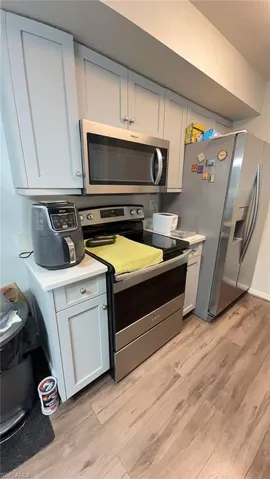 Kitchen featuring shaker-style cabinetry, stainless steel appliances, light-toned countertops, and wood-finish flooring