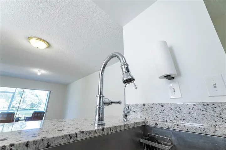 Polished chrome gooseneck faucet with an integrated pull-down sprayer set into a speckled granite countertop