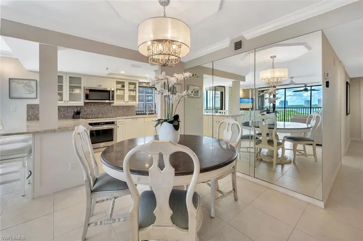 Dining space with ornamental molding, light tile patterned floors, and a chandelier