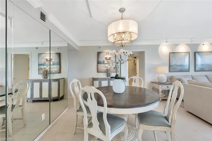 Dining area with a chandelier, light tile patterned floors, and crown molding