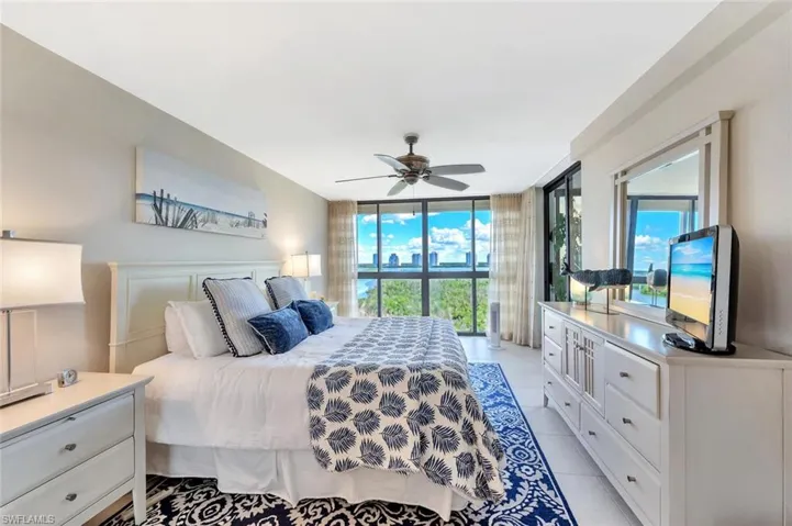 Bedroom featuring a wall of windows, light tile patterned floors, and ceiling fan