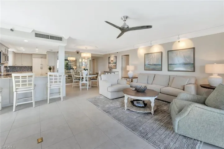 Living room with a ceiling fan, light tile patterned floors, track lighting, and a chandelier