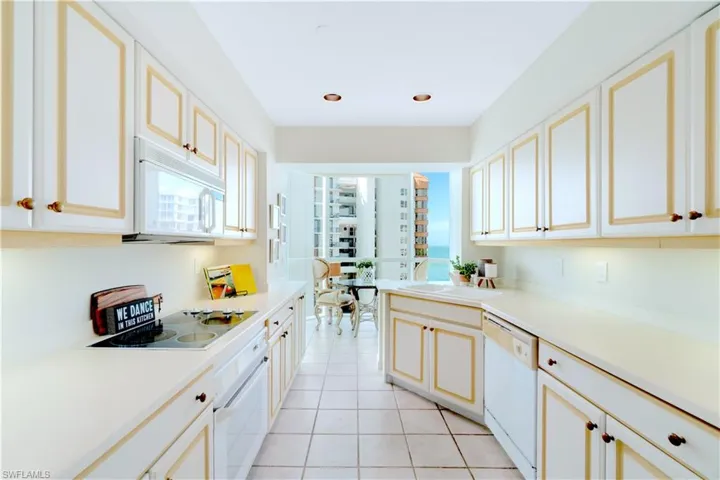Kitchen featuring a healthy amount of sunlight, white appliances, sink, and light tile patterned floors