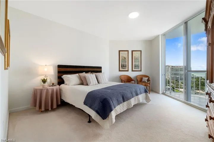 Bedroom with expansive windows, light carpet, and access to exterior