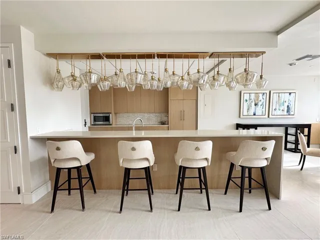Kitchen with sink, stainless steel microwave, pendant lighting, and a kitchen breakfast bar