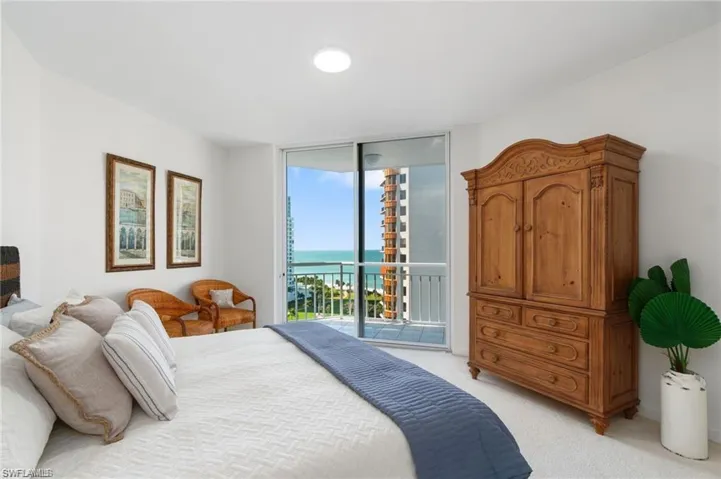 Carpeted bedroom with a water view, access to outside, and expansive windows