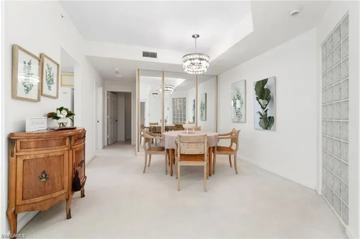 Carpeted dining room with an inviting chandelier