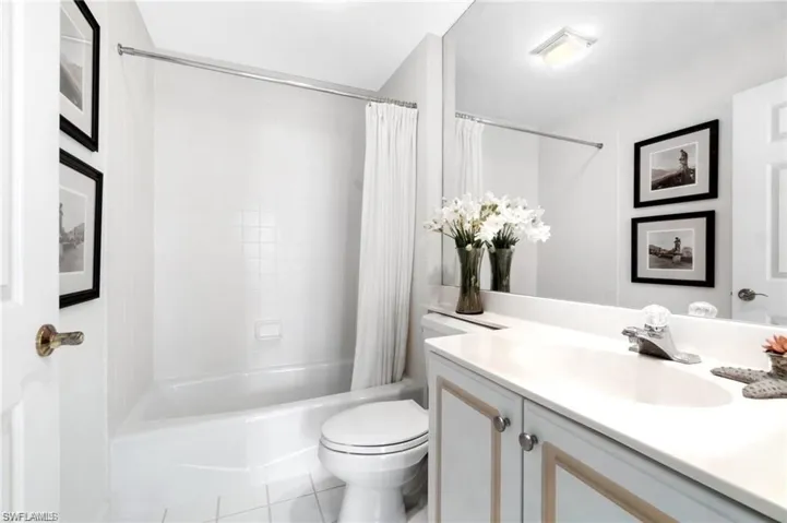 Full bathroom with vanity, shower / tub combo, toilet, and tile patterned flooring