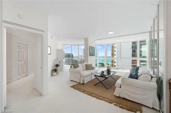 Carpeted living room with a wall of windows and a water view