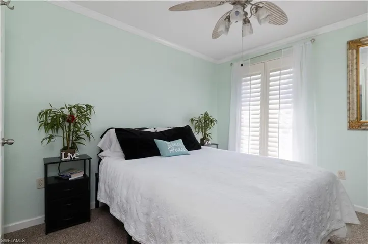 Bedroom featuring dark carpet, crown molding, and ceiling fan