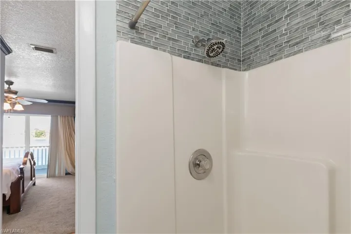 Detailed view of ensuite bathroom, a shower, carpet floors, and a ceiling fan