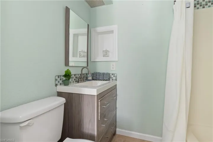 Full bathroom featuring vanity, shower / bath combo with shower curtain, and a textured wall