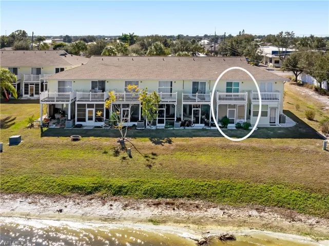 Rear view of property featuring a patio, a yard, a shingled roof, and a balcony