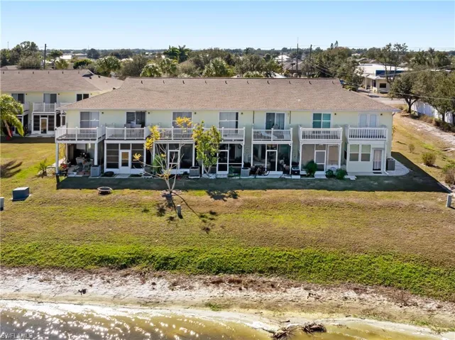 Back of property with a patio area, a lawn, a balcony, and roof with shingles