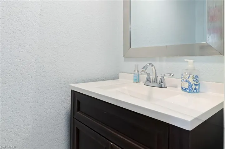 Bathroom with a textured wall and vanity