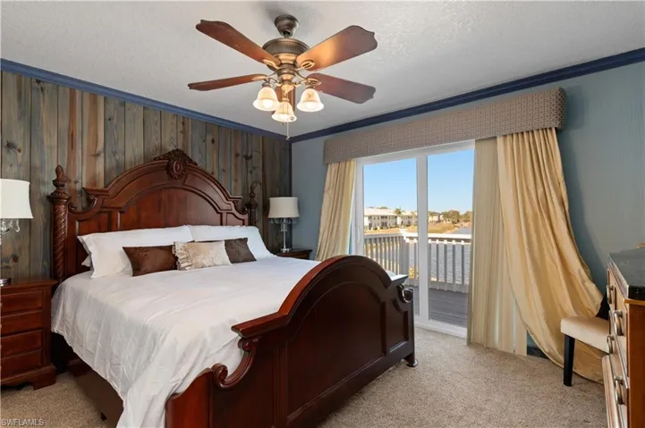 Bedroom featuring wood walls, access to outside, carpet flooring, a textured ceiling, and a ceiling fan