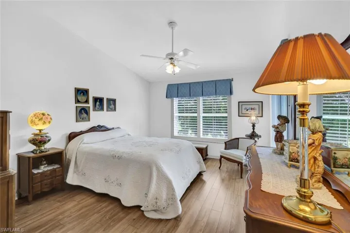 Bedroom featuring hardwood / wood-style floors, ceiling fan, vaulted ceiling, and multiple windows