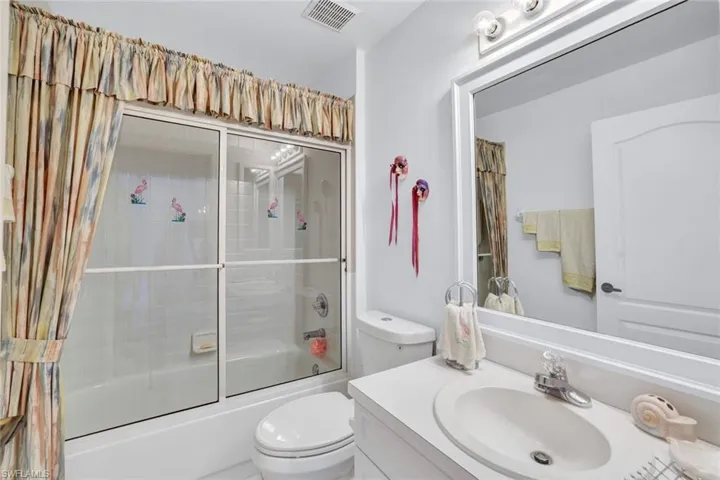 Full bathroom featuring toilet, vanity, and combined bath / shower with glass door
