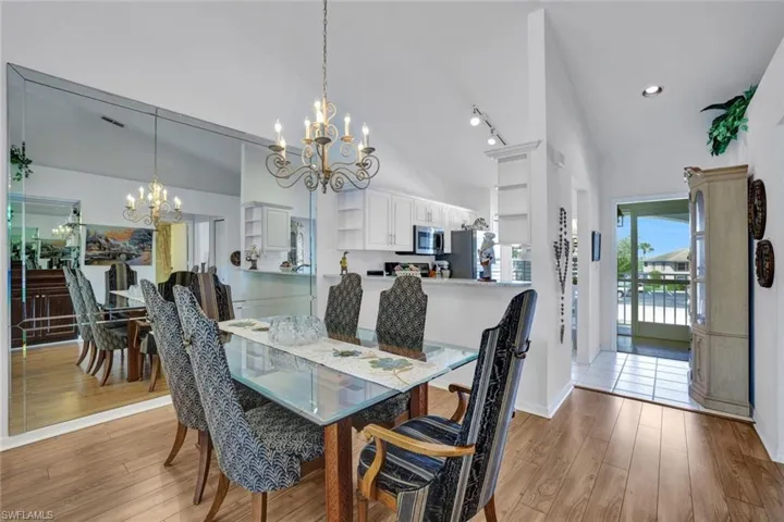 Dining area featuring a chandelier, rail lighting, high vaulted ceiling, and light hardwood / wood-style flooring